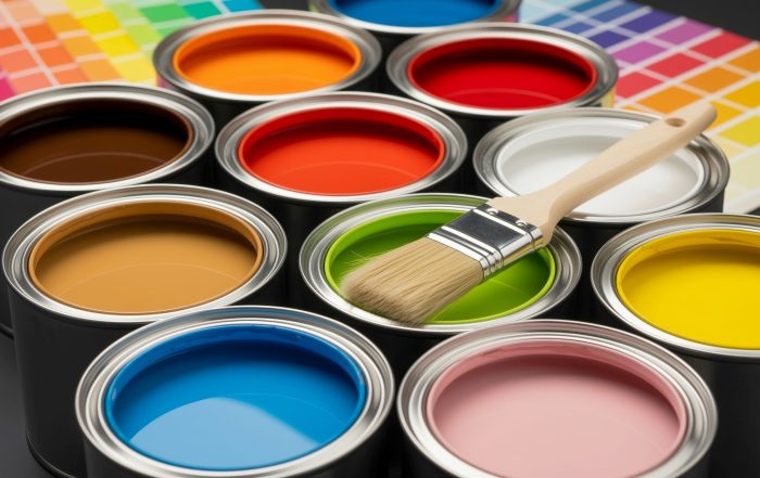 viele offene Farbtöpfe mit bunten Farben und einem Pinsel darüber